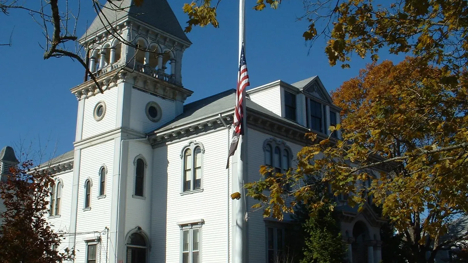 Marion Town Hall, a white Victorian building with a tall bell tower framed by autumn foliage, Marion, Massachusetts