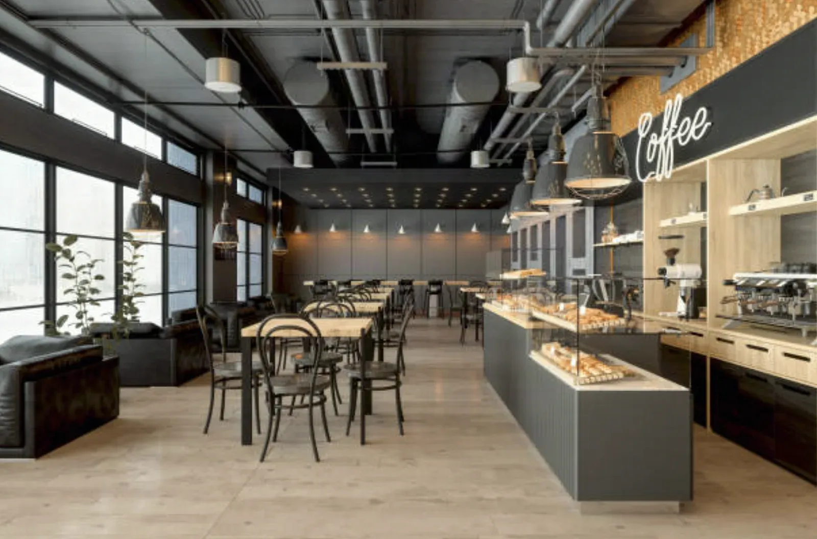 Café interior with an open black ceiling and exposed ductwork, industrial pendant lights, a pastry display counter, and bentwood chairs along a glass wall