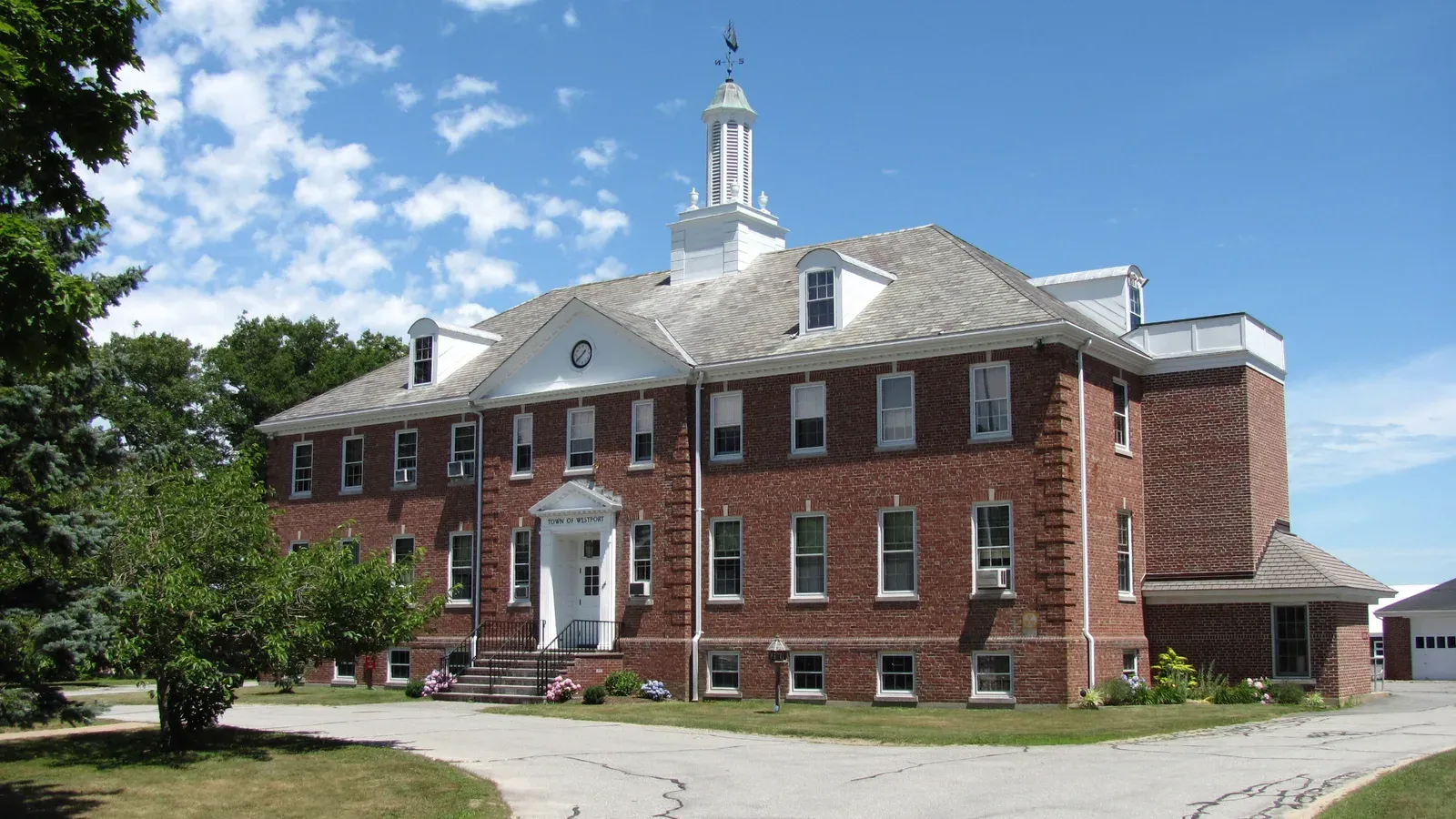 Westport Town Hall, a red-brick Colonial Revival building with a white cupola and dormers under a blue sky, Westport, Massachusetts